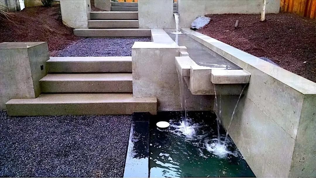 Detailed view of the multi-level concrete waterfall feature with water flowing between tiers.