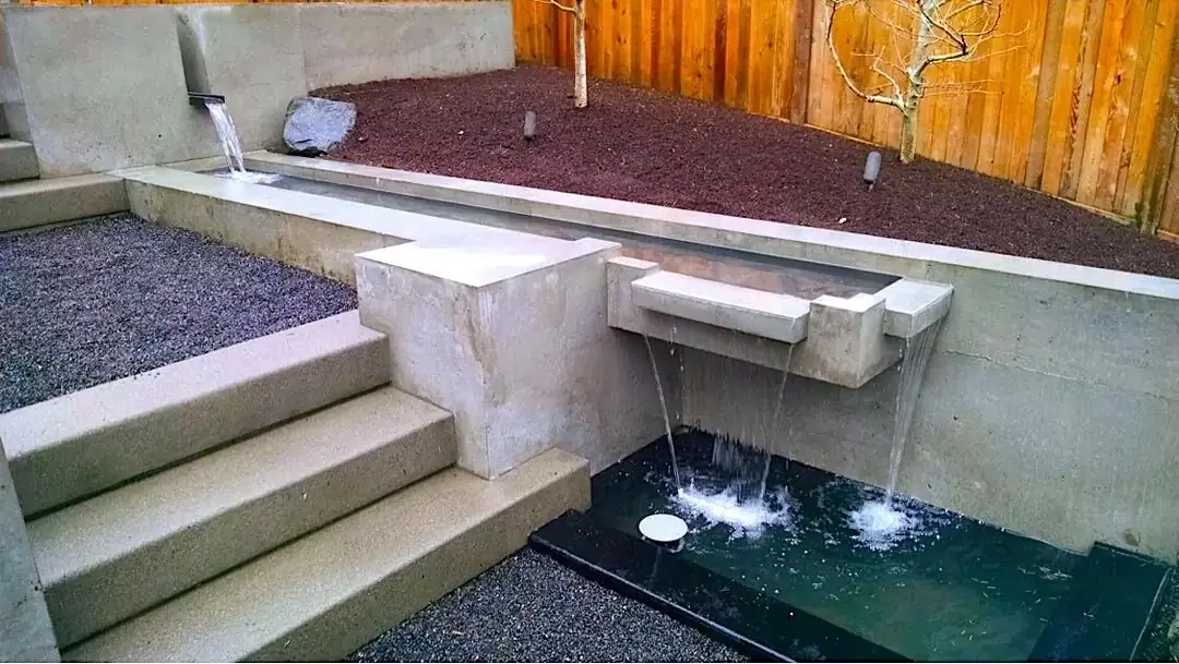 Side angle of the concrete retaining wall with two separate spillways creating a dynamic waterfall effect.