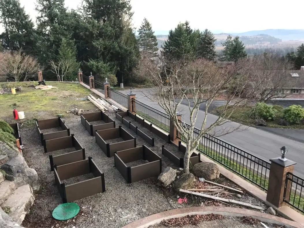 Installation of tiered retaining wall planters on a gravel base for a residential garden project in Puyallup.