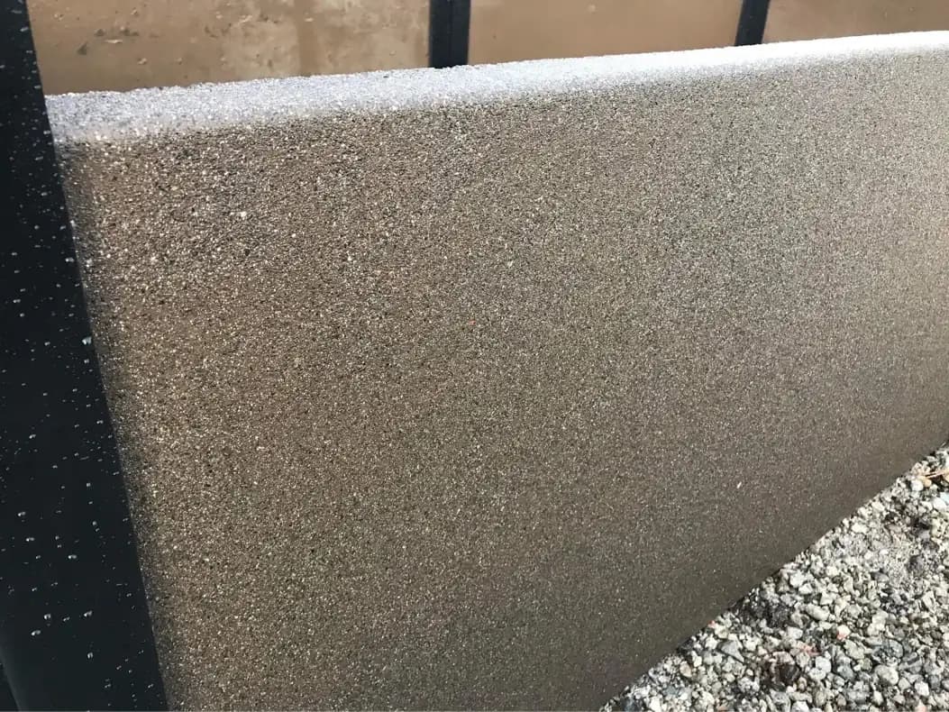 Detailed close-up of the exposed aggregate finish on a concrete retaining wall panel, showing stone texture.