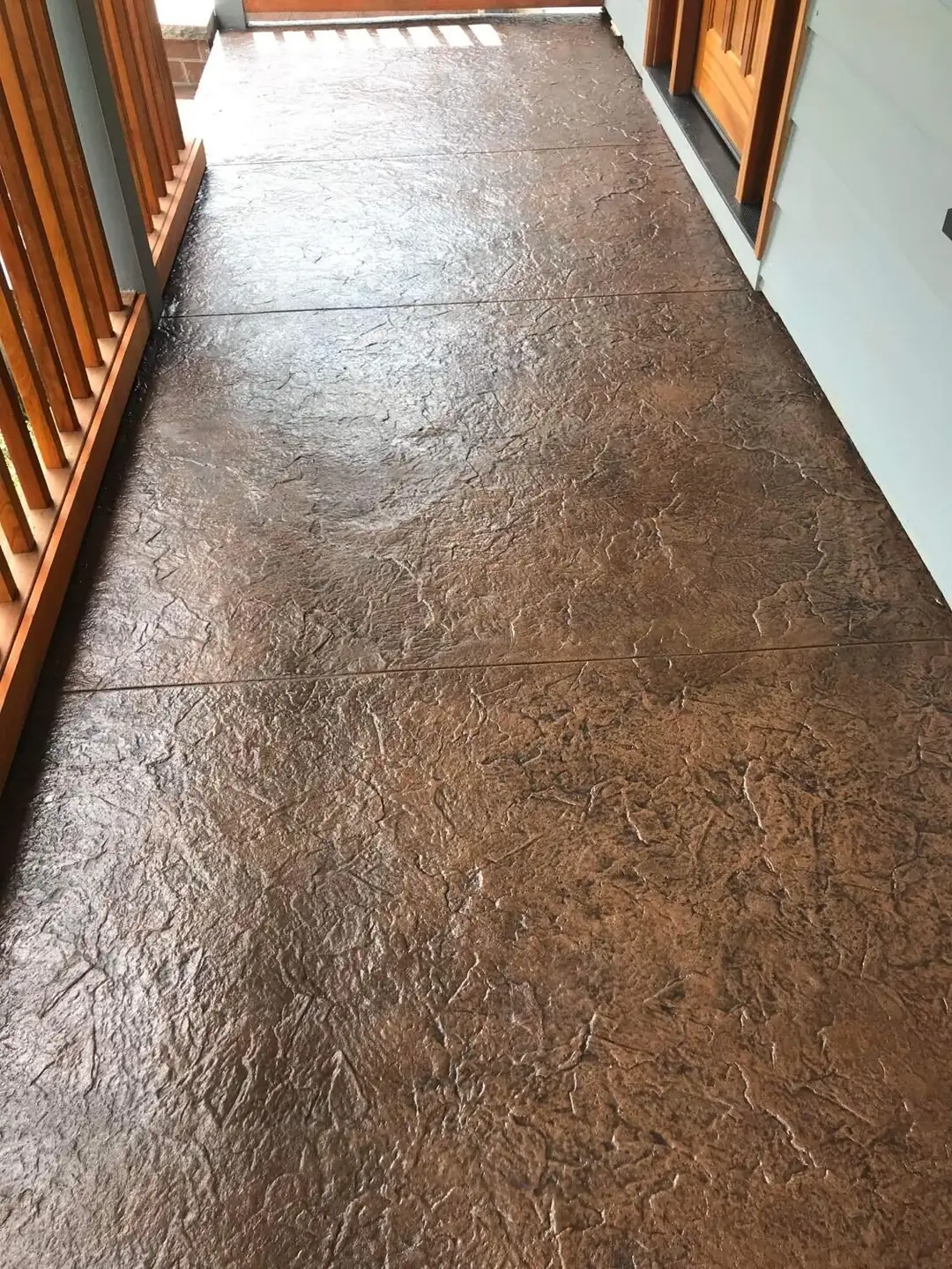 Stamped concrete porch landing with a random stone texture and saw-cut control joints.