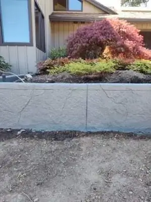 Close-up view of the textured stamp pattern and vertical control joint on a concrete retaining wall in Vashon, WA.