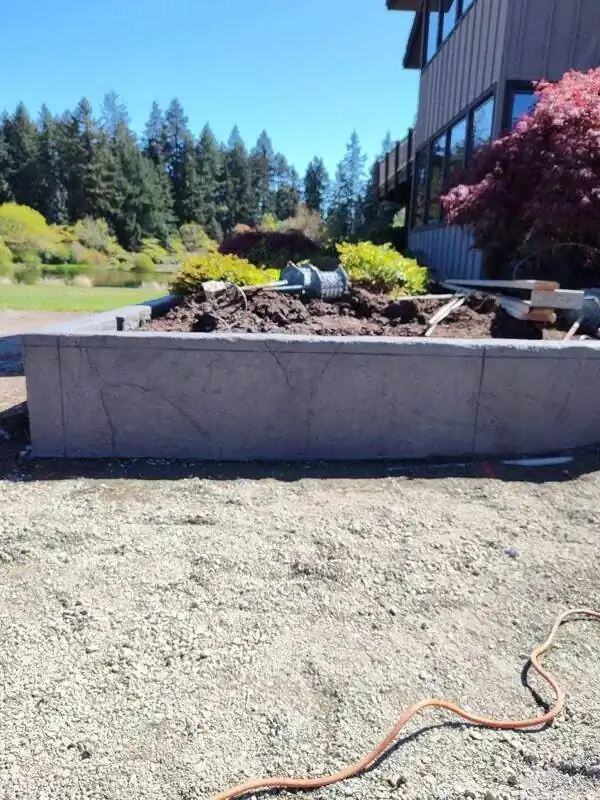 Side profile of a new stamped concrete planter wall set against a gravel base in a Vashon, WA landscape project.