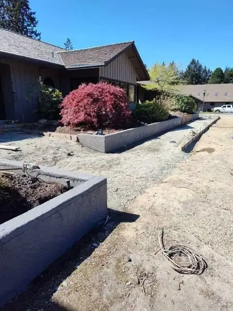 Wide view showing multiple stamped concrete retaining walls and forming for adjacent flatwork.
