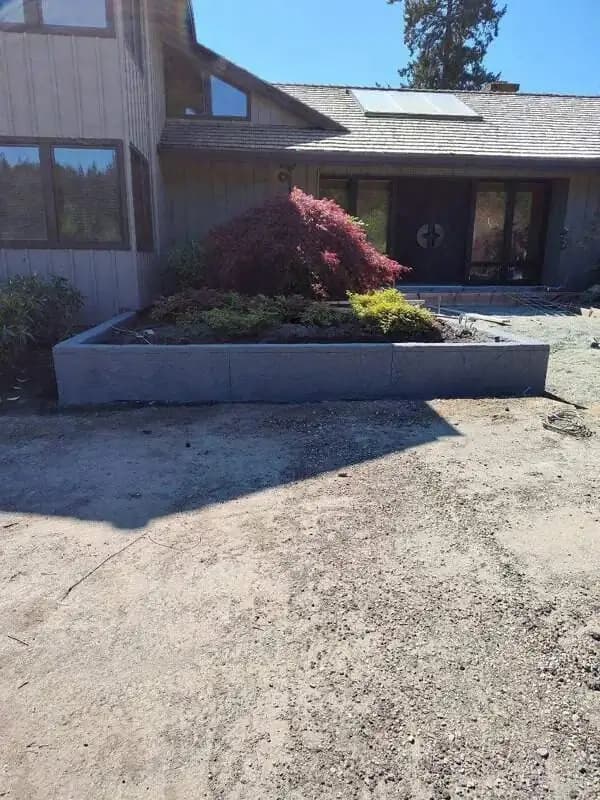 Front view of a completed concrete raised garden bed integrated with the home's entryway.