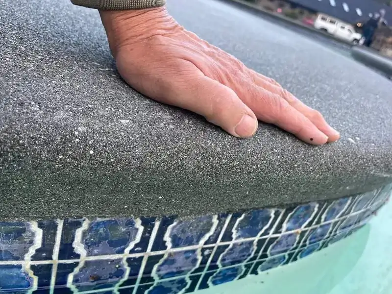 Close-up of the fine sand finish texture on the bullnose pool coping in Vashon, showing the smooth edge.