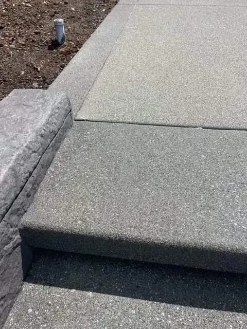 A side angle of the exposed aggregate steps showing the clean, rounded edge profile against a retaining wall.
