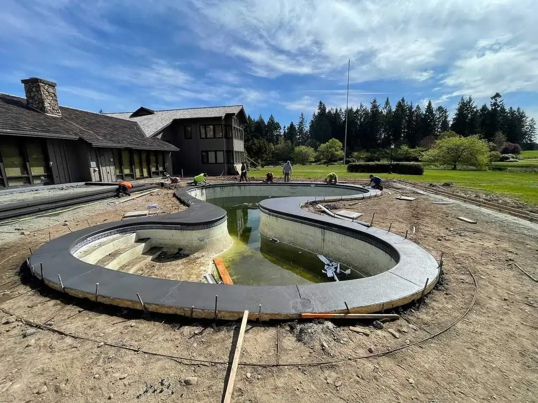 The pool deck during construction, showing the complex formwork and rebar set for the custom curved coping.