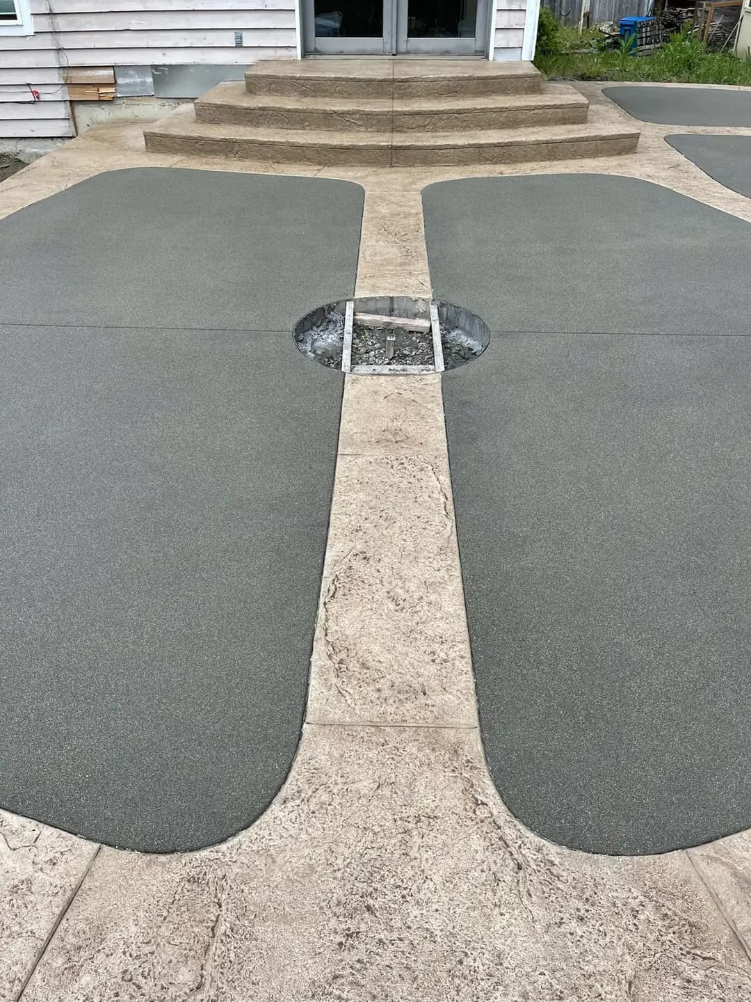 Close-up of a custom concrete patio in Puyallup, showing the central cutout for a fire pit and two-tone finish.