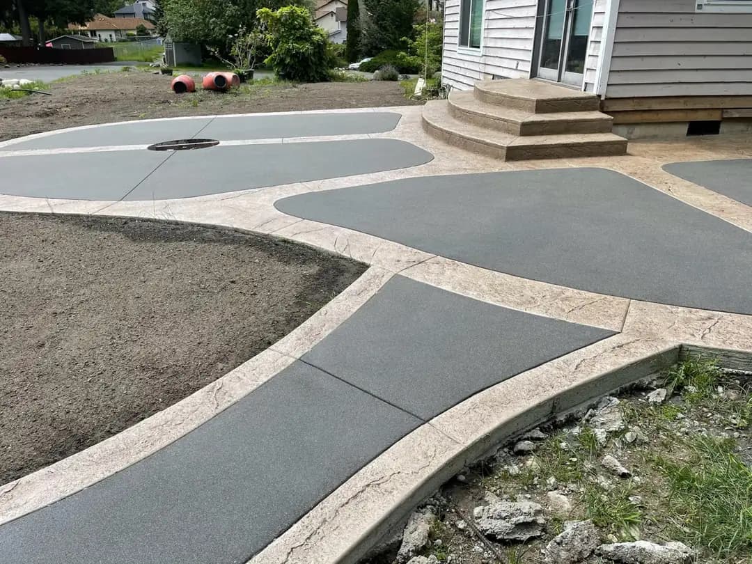 A curved concrete walkway with a stamped border connecting to a larger patio with integrated stamped steps.
