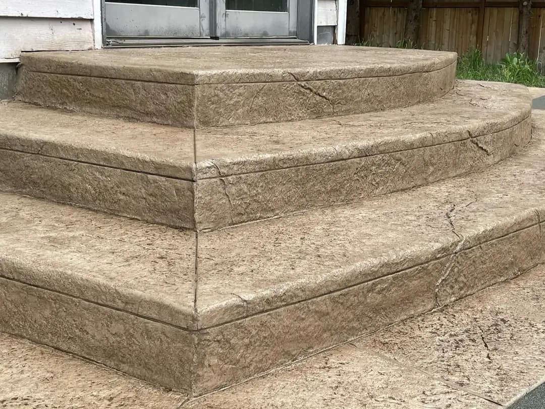 Detailed view of curved, stamped concrete steps with a large stone texture and defined, clean edges.