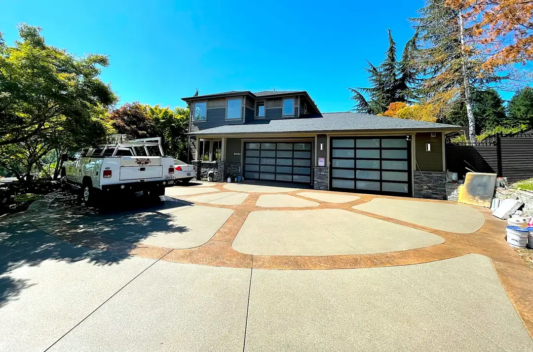 A modern two-tone concrete driveway with artistic stamped inlays in front of a home in Puyallup, WA.