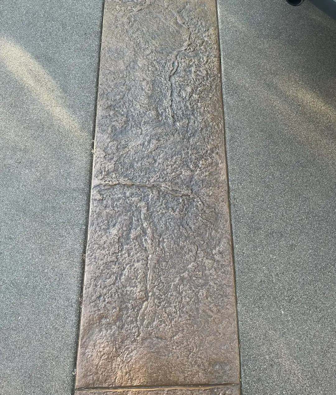 Close-up detail of the large-stone stamped concrete texture next to the fine sand finish.