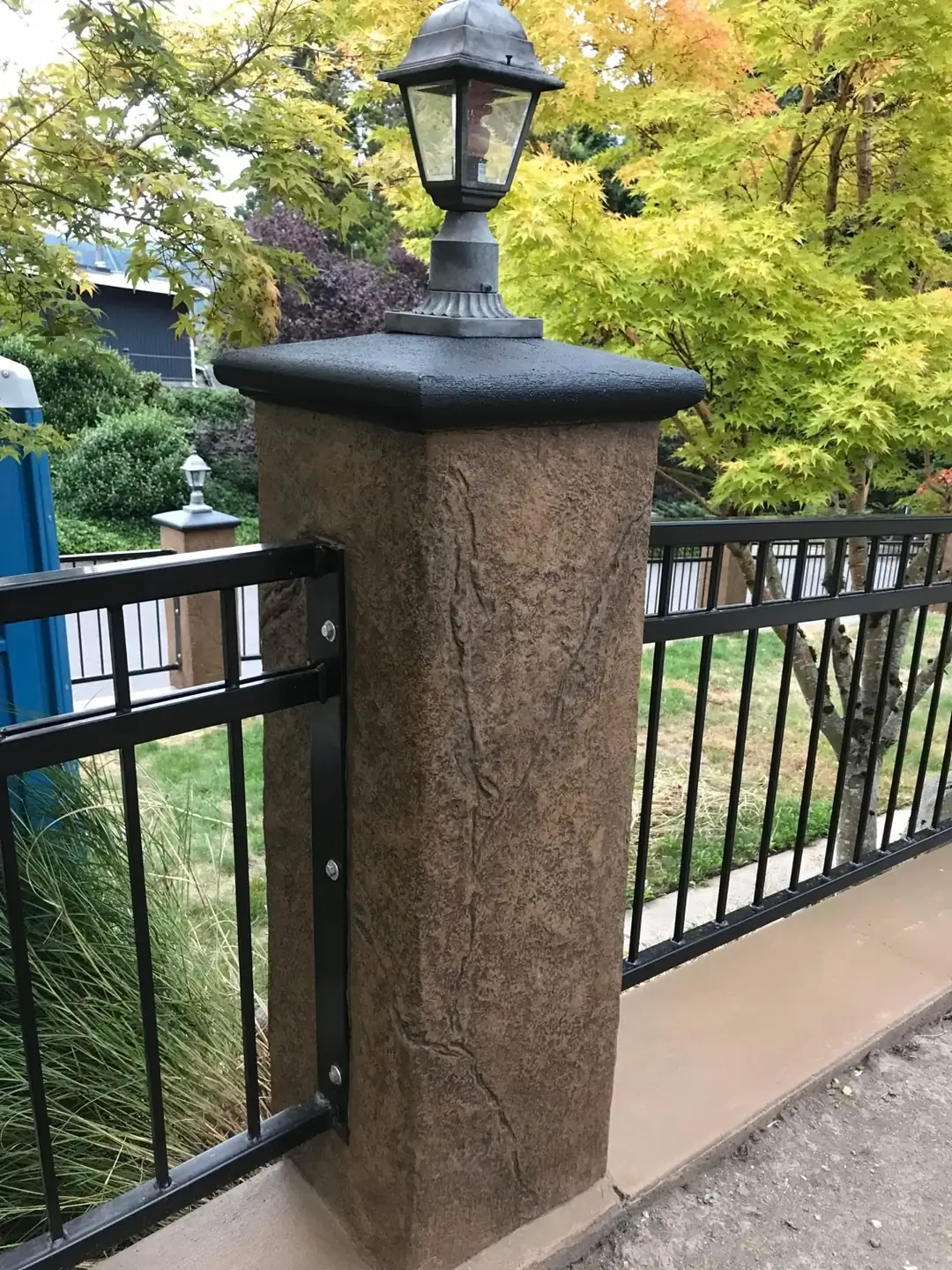 A decorative concrete column with a stamped finish matching the driveway's border.