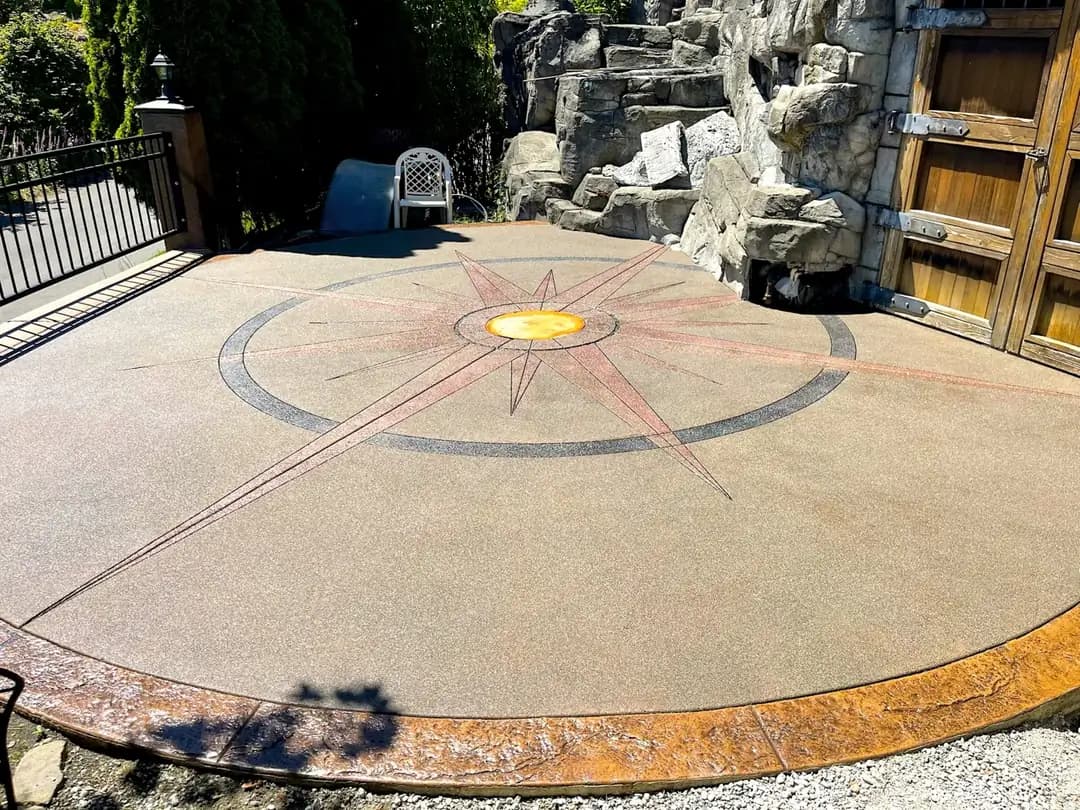 Finished custom concrete patio in Puyallup with a multi-color exposed aggregate compass rose and stamped border.