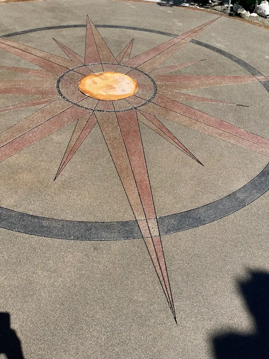 Detailed view of the multi-colored exposed aggregate compass, showing the red, grey, and gold sections.