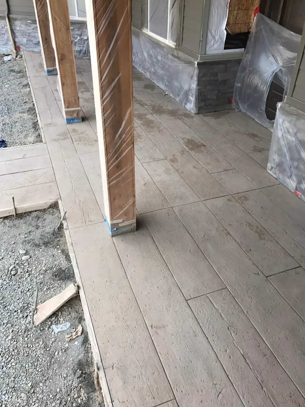 Freshly stamped concrete porch with a wood plank texture, shown before staining and sealing.