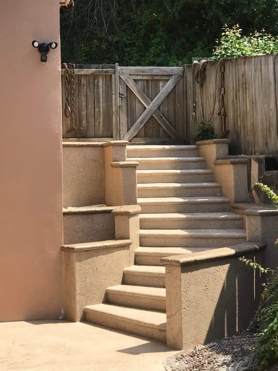 Frontal perspective of the grand stamped concrete staircase leading up to a wooden gate and fence.