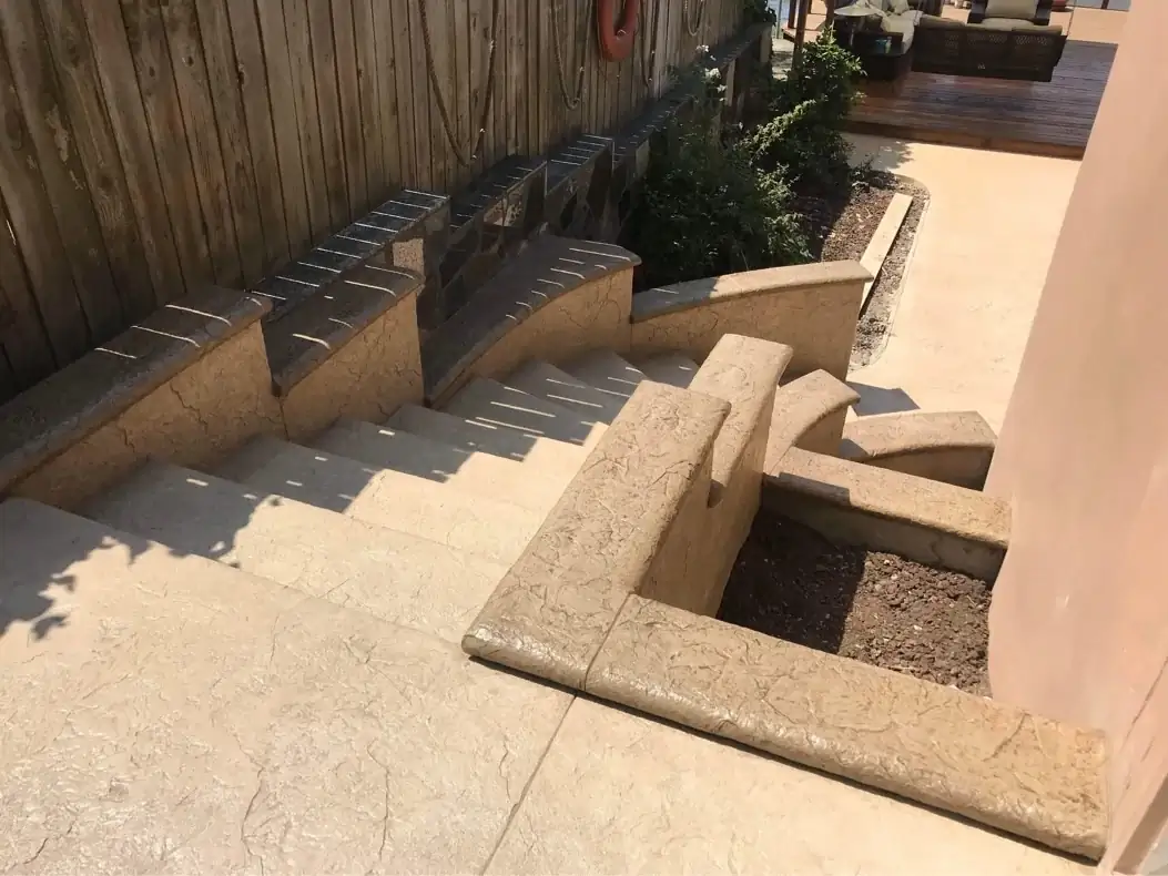 Overhead view looking down the custom concrete staircase, showing the curved retaining walls and patio.