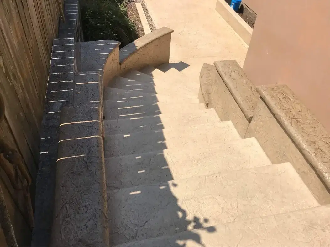 High-angle shot capturing the strong shadow lines across the textured concrete steps and walkway.