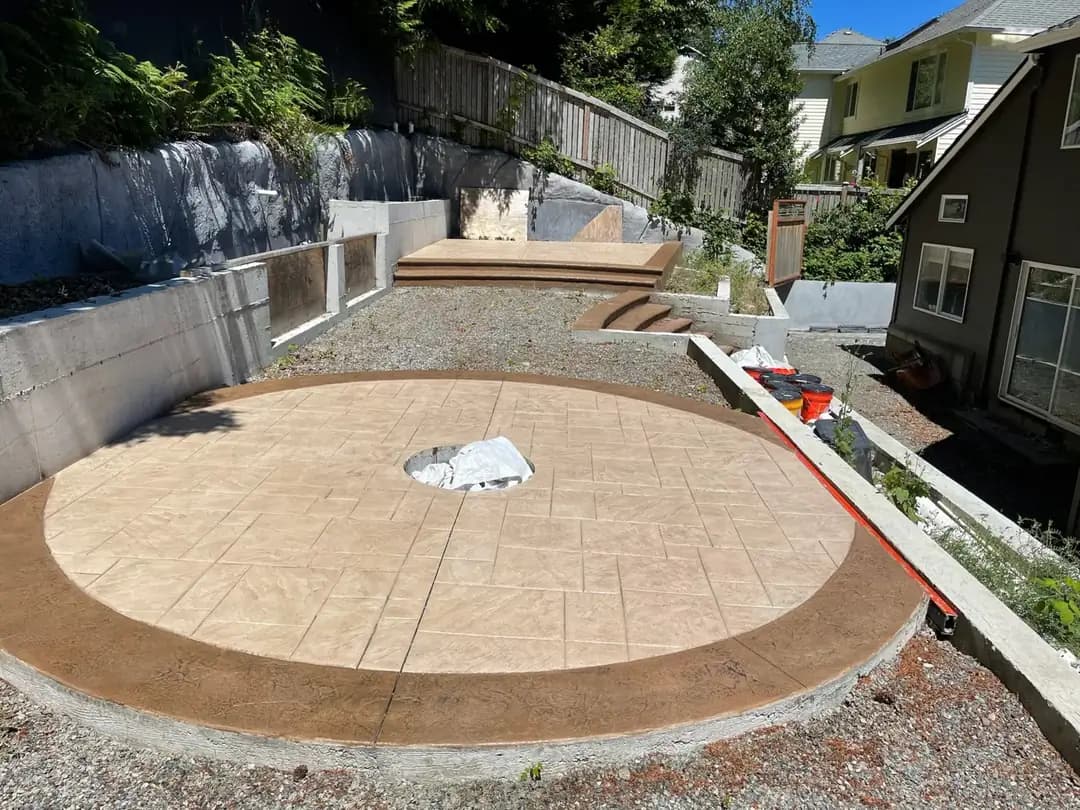 Circular stamped concrete patio with a central fire pit opening and a contrasting dark, textured border.