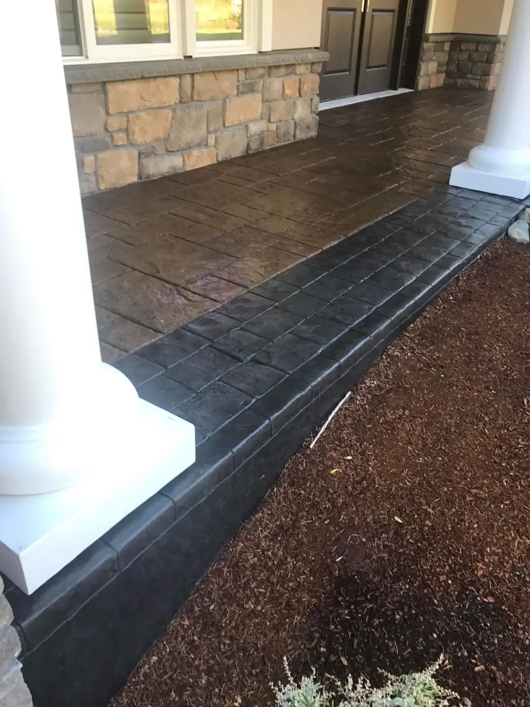 Detail of the stamped concrete curb in Tacoma, showing the dark charcoal color and texture next to a white pillar.