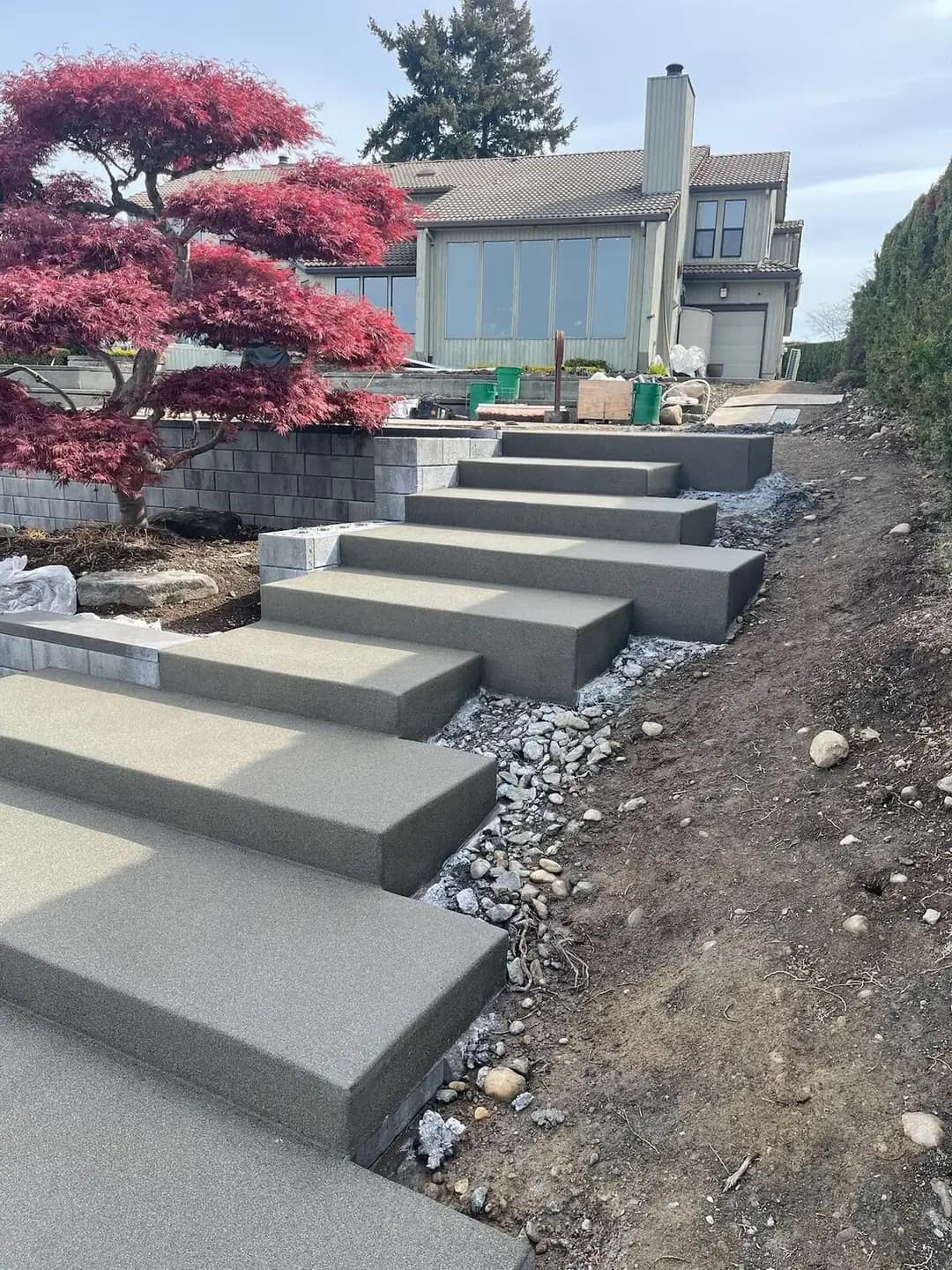 Side profile of modern floating concrete steps with an exposed aggregate finish in Puyallup, WA, next to a garden.
