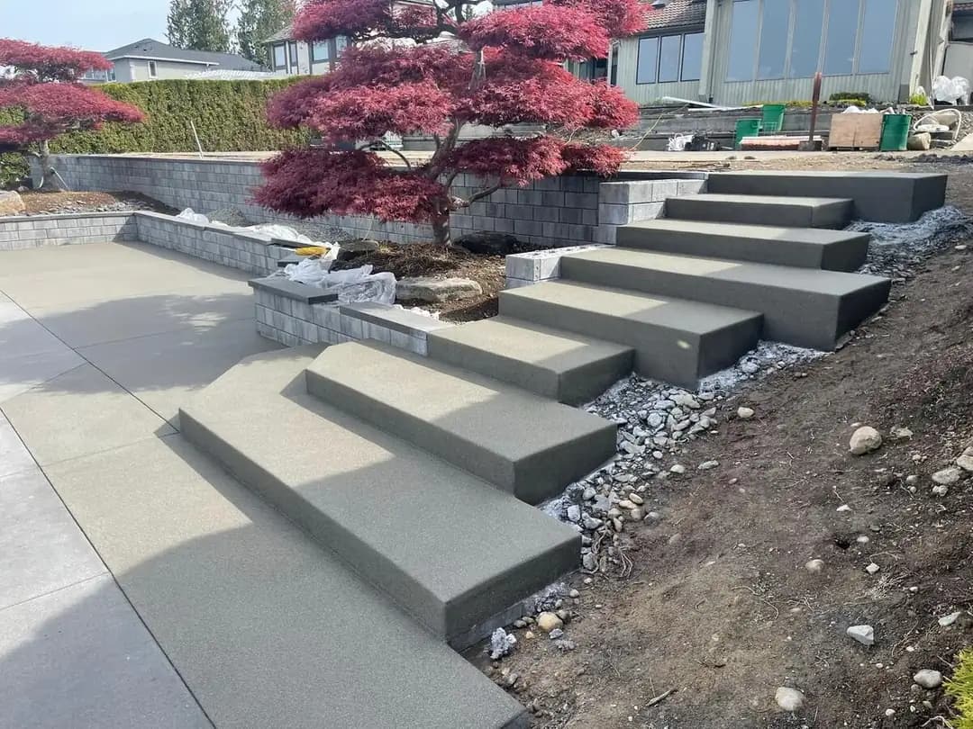 Wide view showing the integration of floating concrete steps with a new block retaining wall and patio.