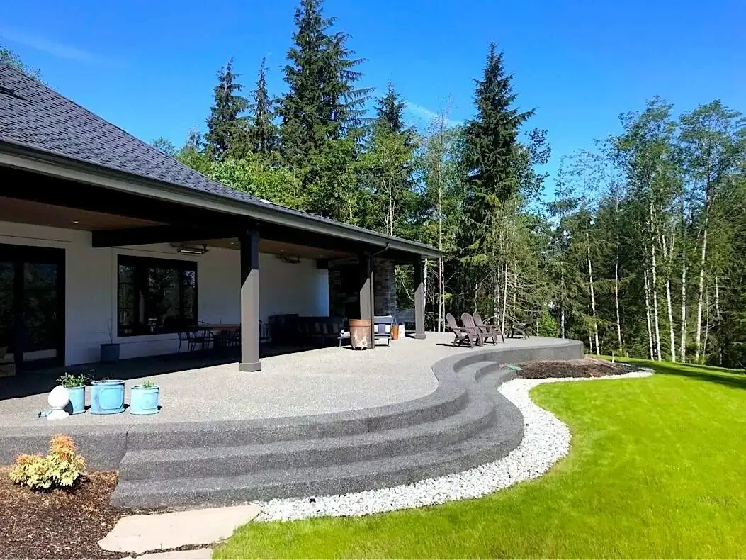 Wide view of a multi-level exposed aggregate concrete patio with sweeping curves in Tacoma, WA.