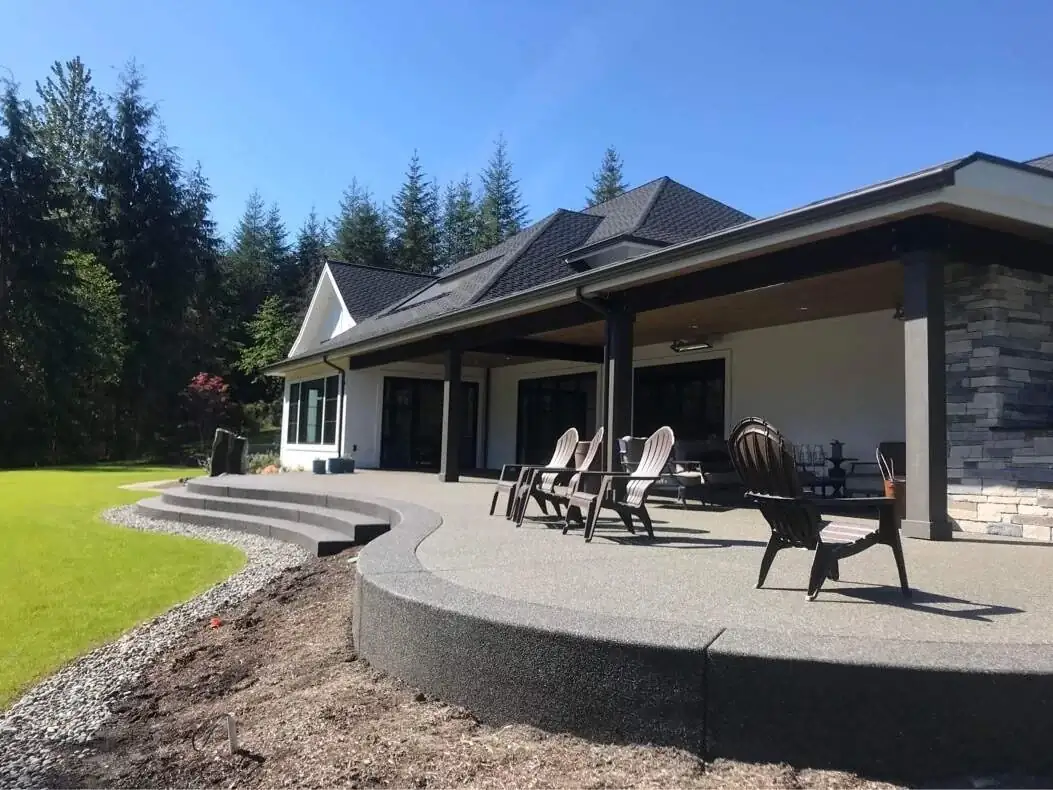 Side profile of a large, curved exposed aggregate patio and steps recently completed in Tacoma, WA.