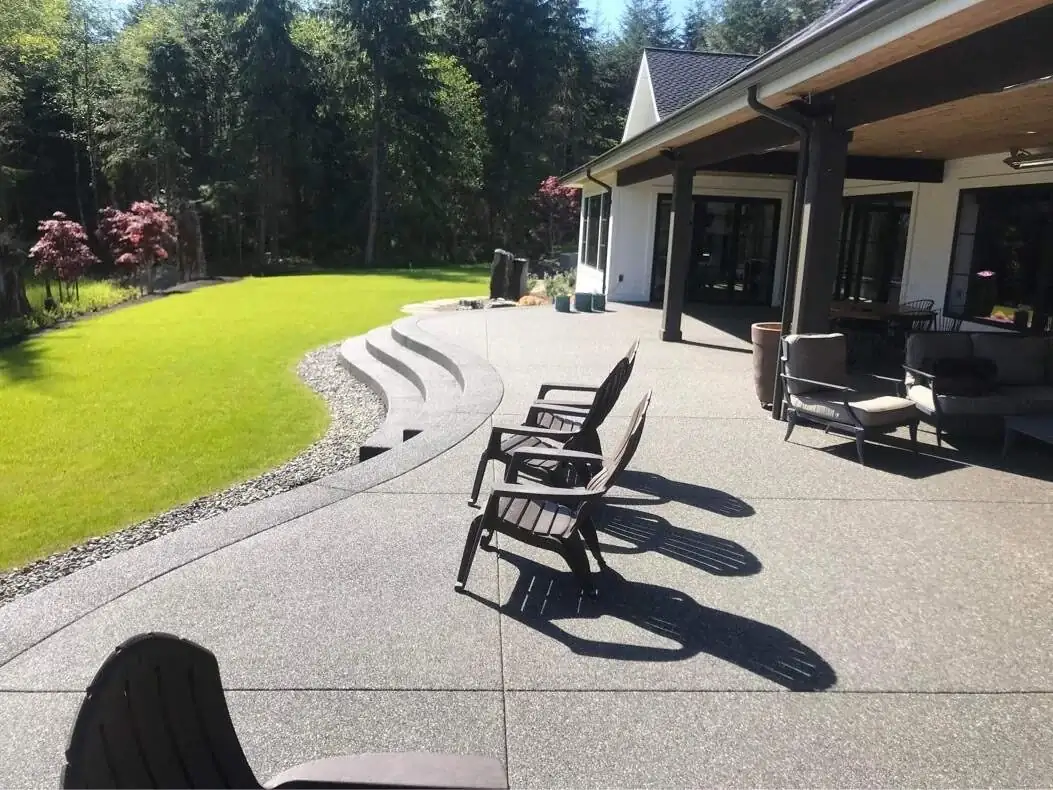 View across the finished exposed aggregate patio surface in Tacoma, showing saw-cut joints and curved steps.