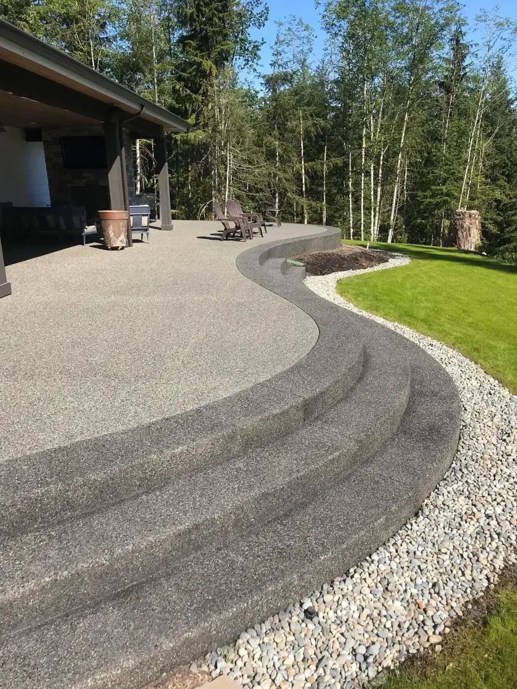 Detail shot of the wide, curved concrete steps with an exposed aggregate finish connecting two patio levels.