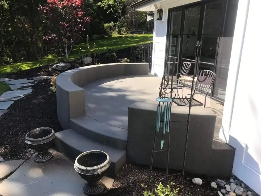 A separate raised concrete landing with an integrated curved seat wall and exposed aggregate finish.