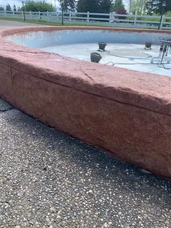 Angled perspective of the curved, reddish-brown stamped concrete fountain wall in Enumclaw, WA.