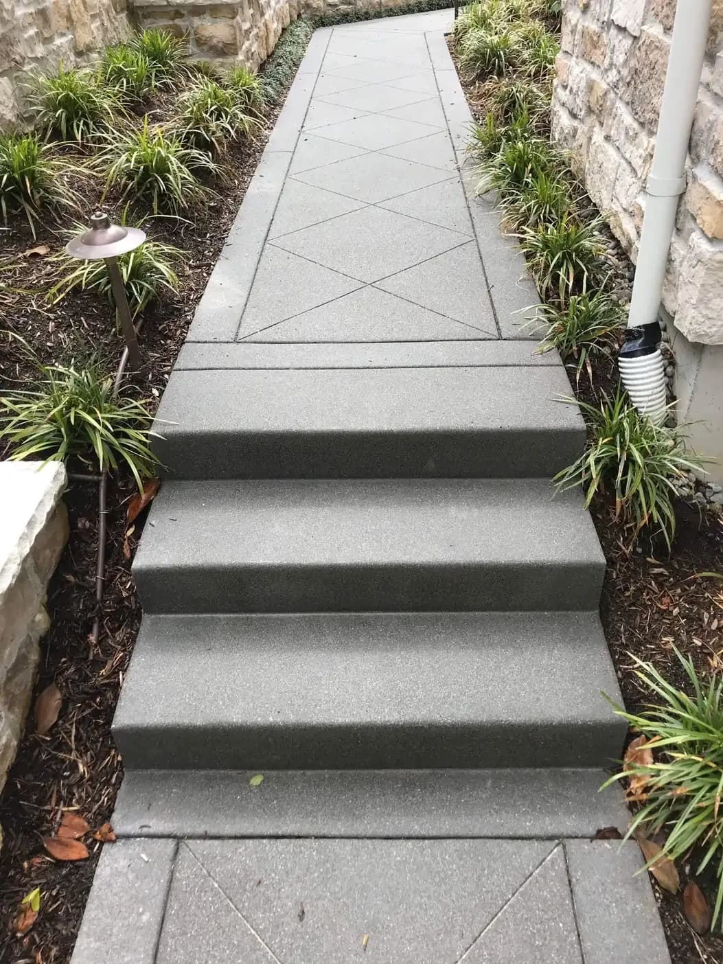 Close-up of clean, modern exposed aggregate concrete steps on a garden path in Bellevue with linear saw cuts.