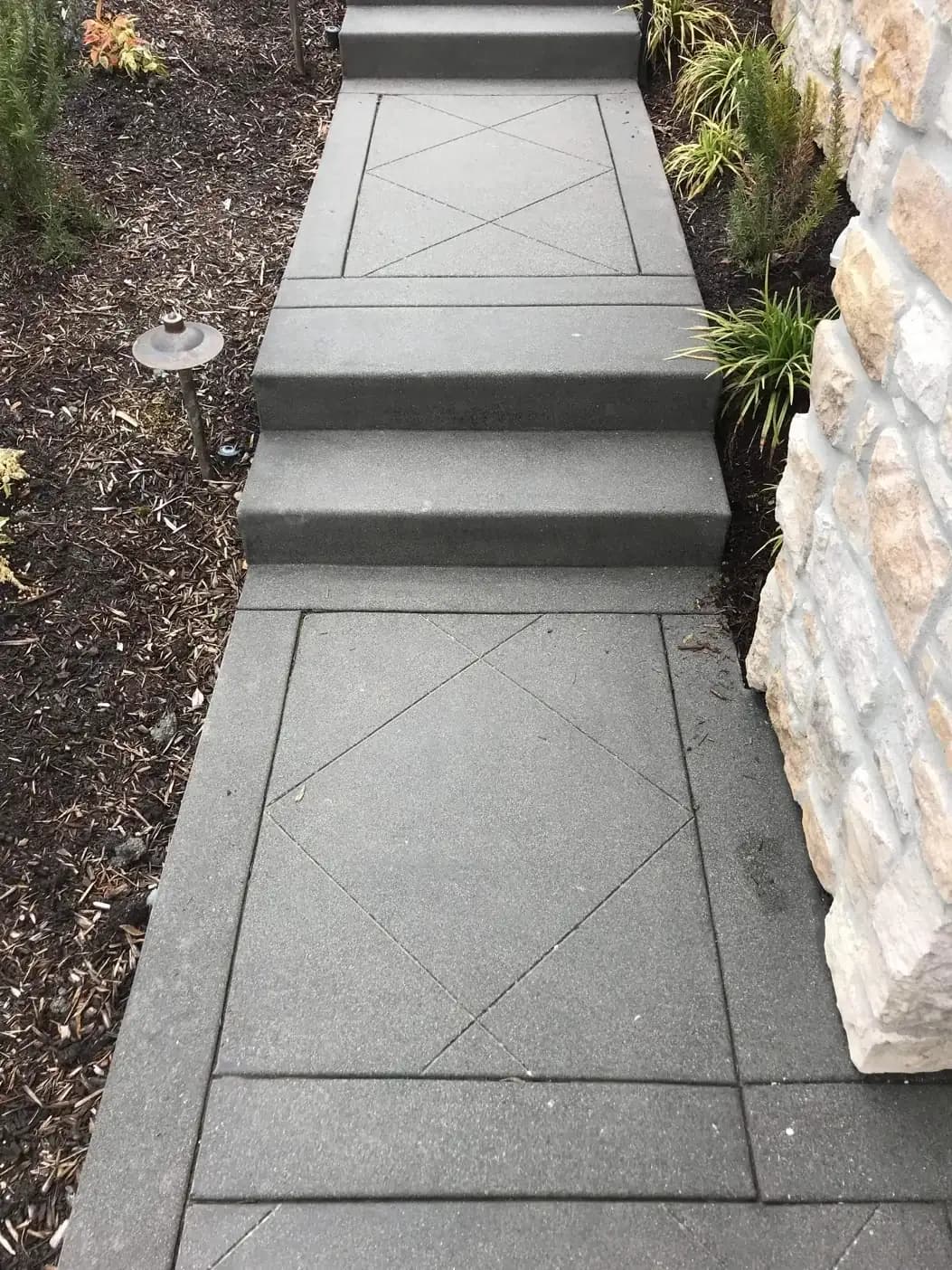 View looking down a set of concrete steps with a consistent exposed aggregate finish and decorative saw cuts.