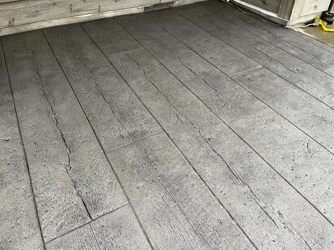 Detailed angle of a wood grain stamped concrete patio in Puyallup, showing the authentic texture and plank lines.